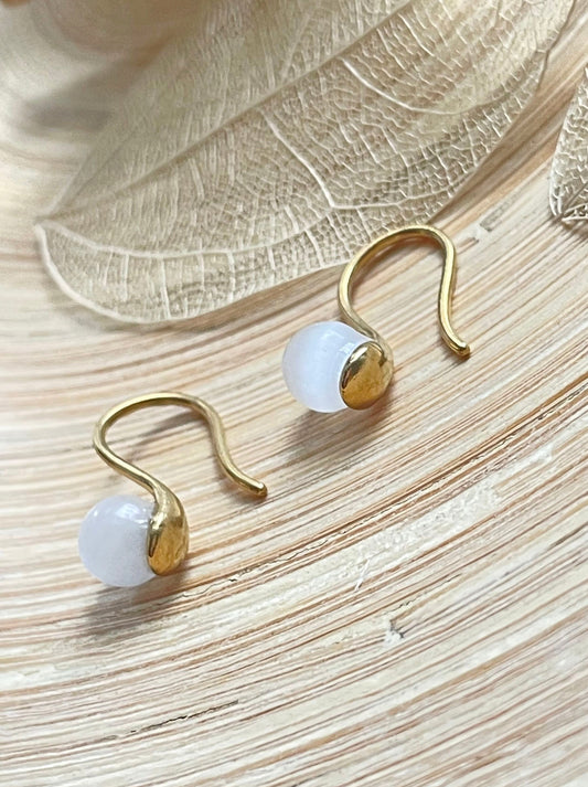 SELENITE BEAD HUGGIE Gold earrings wooden surface