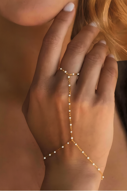 Gold bracelet with small beads on a hand against a blurred background